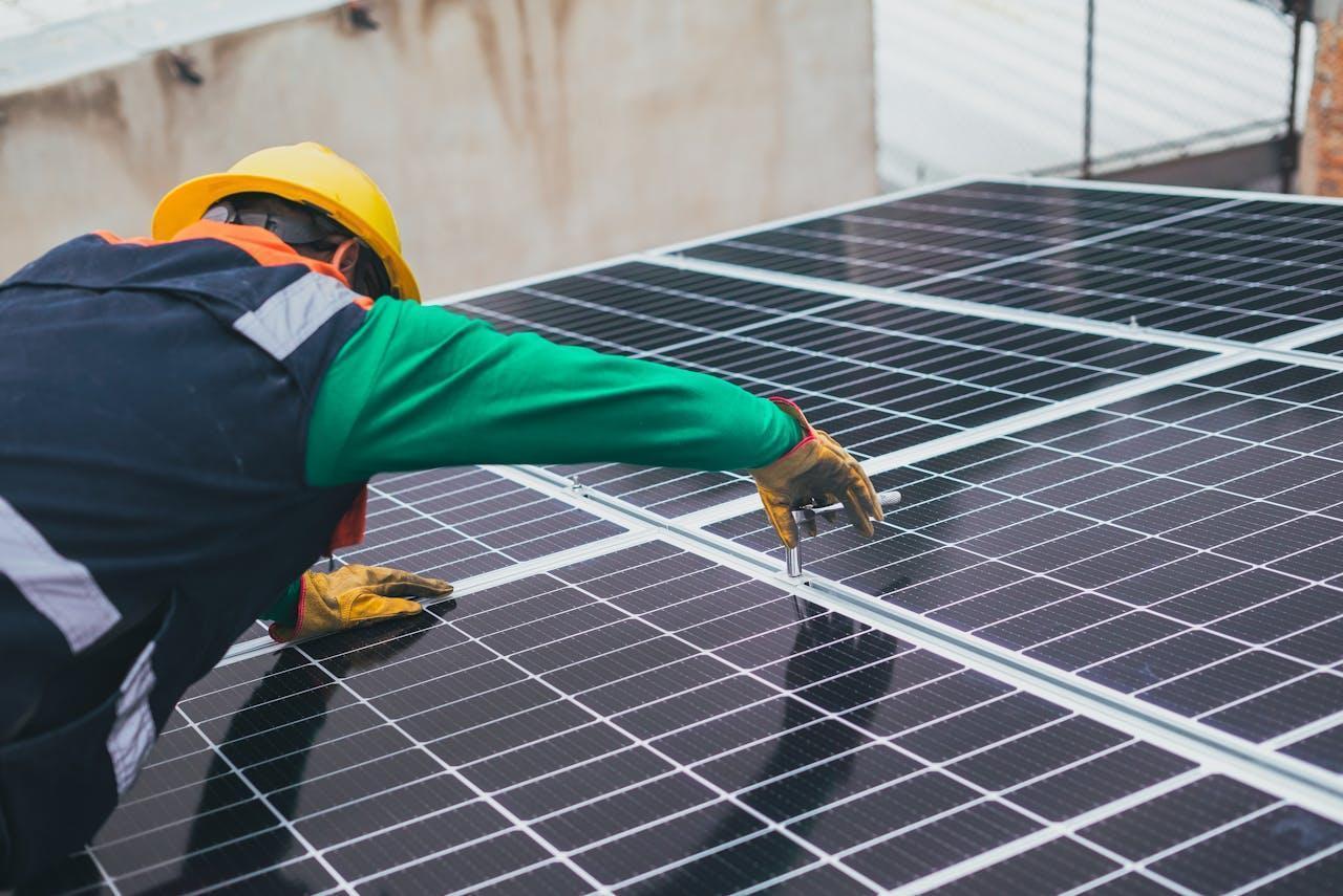 A man installing solar panels on top of the roof