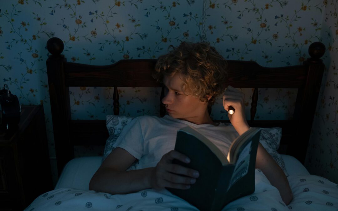 Teenager reading in bed with a flashlight