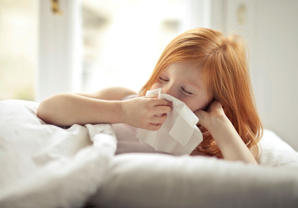 A little girl wiping her nose with a tissue
